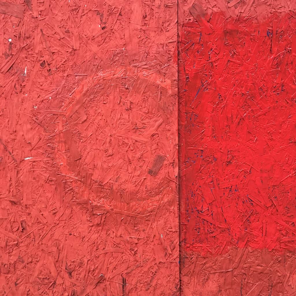 plywood painted a brilliant bright orange red with a double circle design to the left of a crease