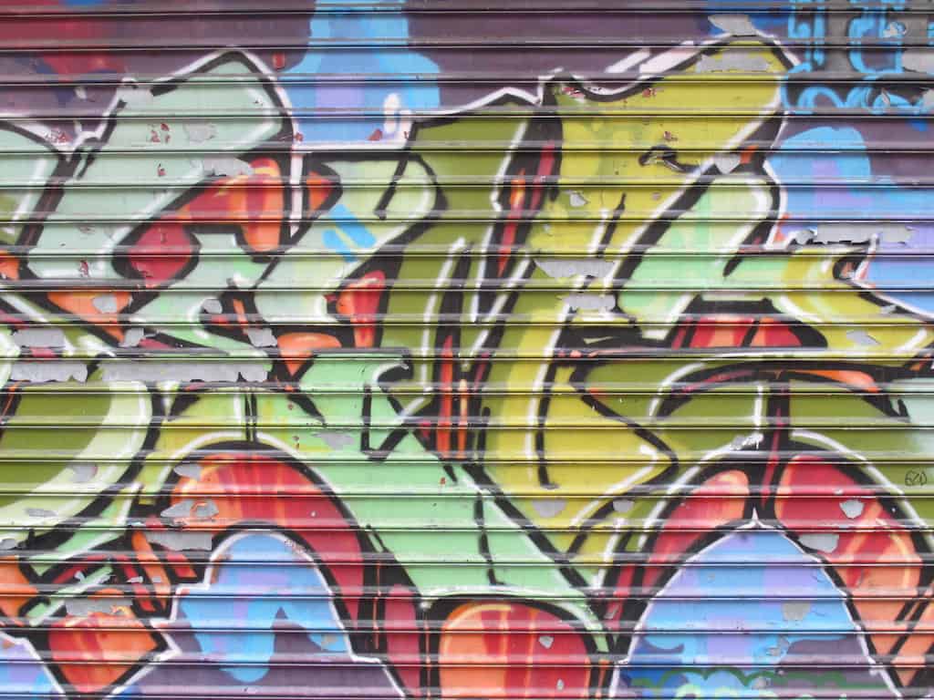 NYC garage door covered in graffiti with reds, blues, yellows and greens