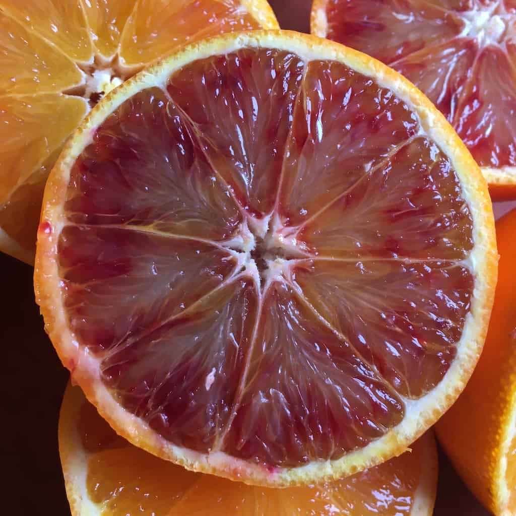 closeup of a sliced Tarocco Blood orange with its gemstone colors or ruby red, lemon yellow and orange