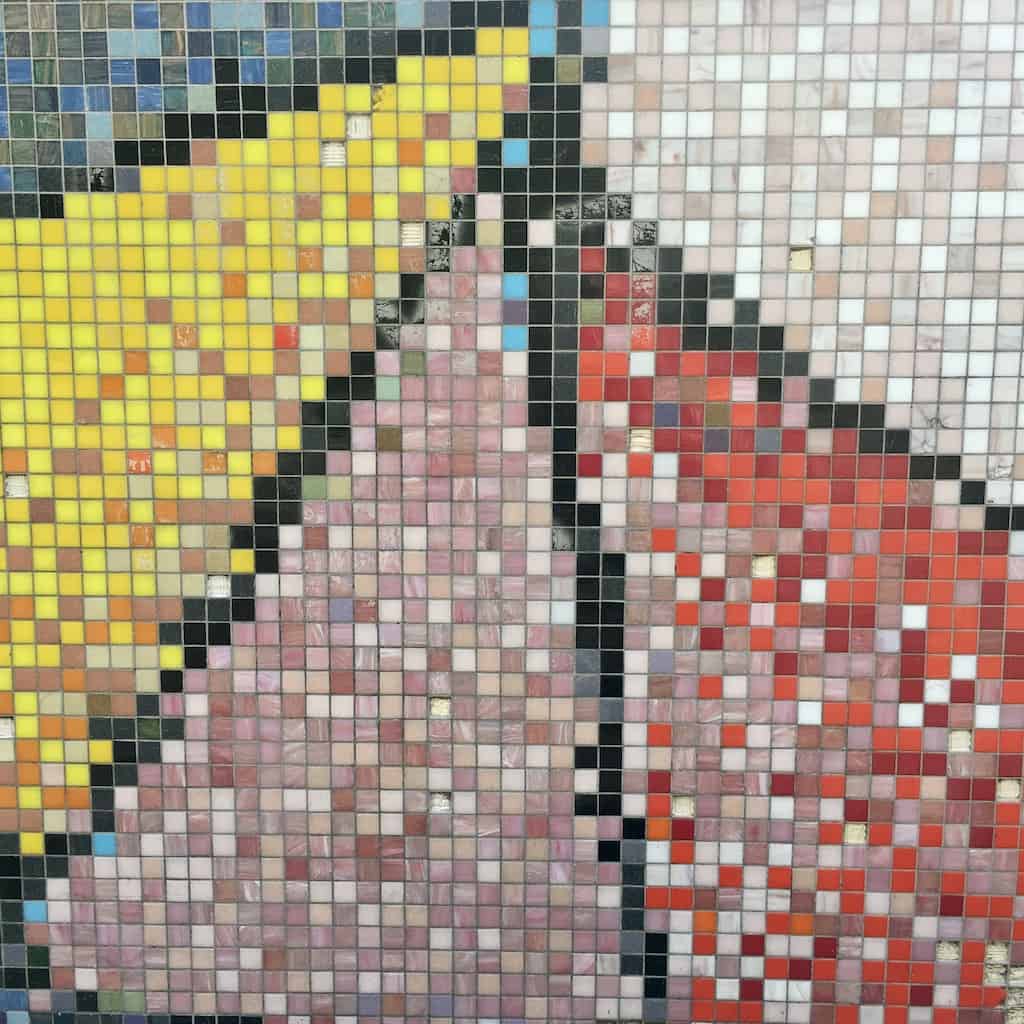 a portion of a city wall with small mosaic tiles fanning out in a triangular pattern with blue, yellow, mauve, red, and grey tiles each section outlined in black (made to look like vintage computer graphics)