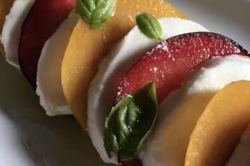 plum and mozzarella caprese salad with basil leaves and olive oil on a plate