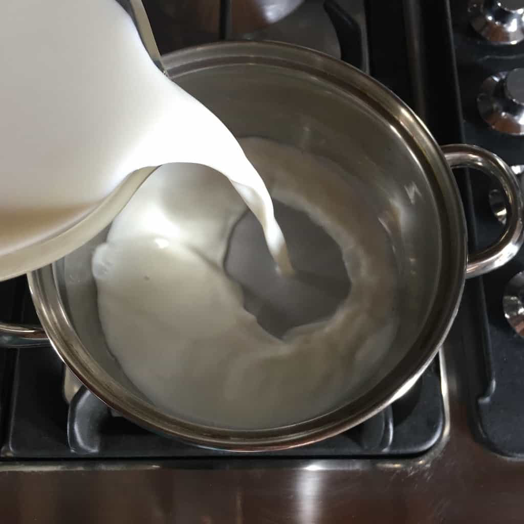 milk pouring from a measuring cup into a pot