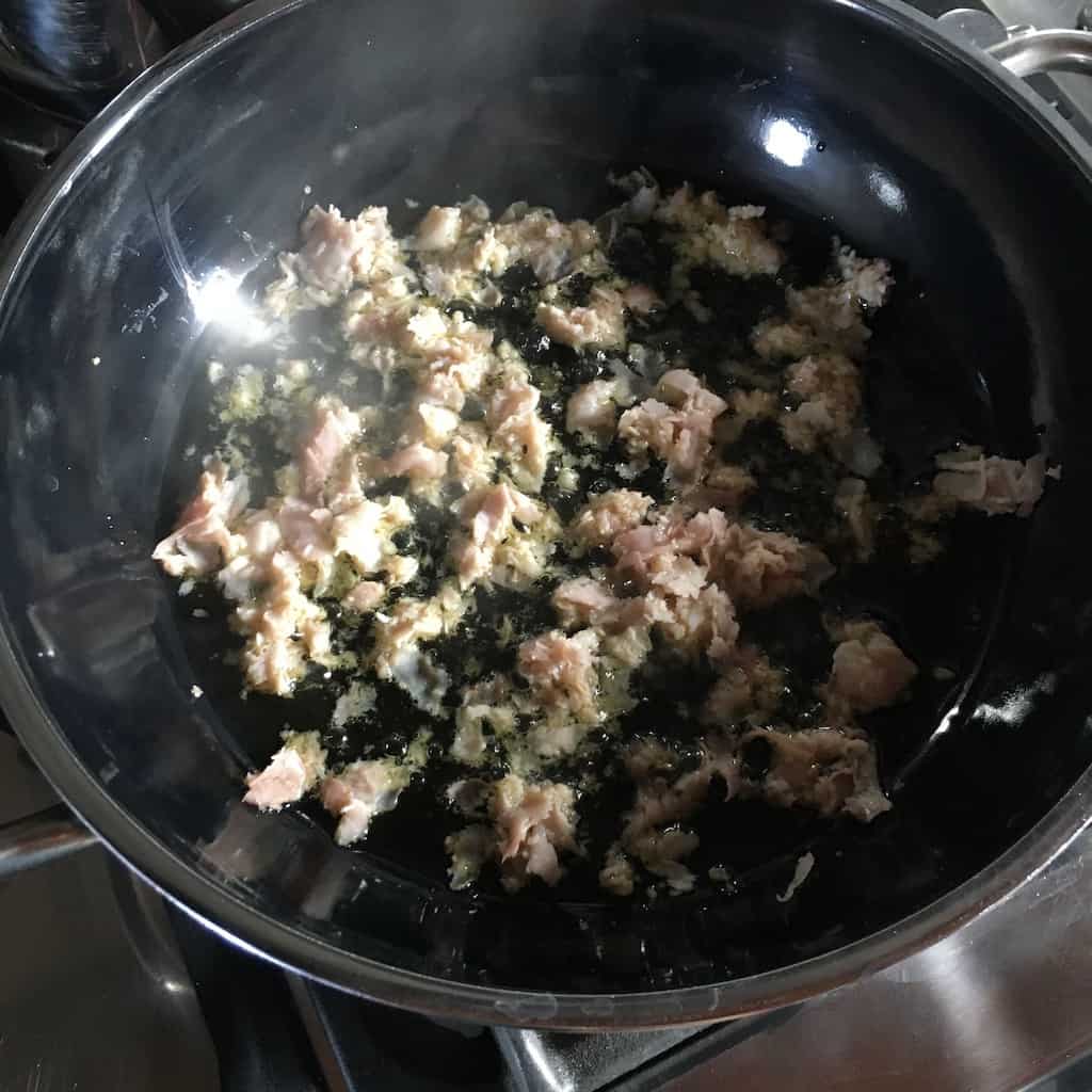 prosciutto ham cooking in a navy blue Silit Brand skillet with olive oil