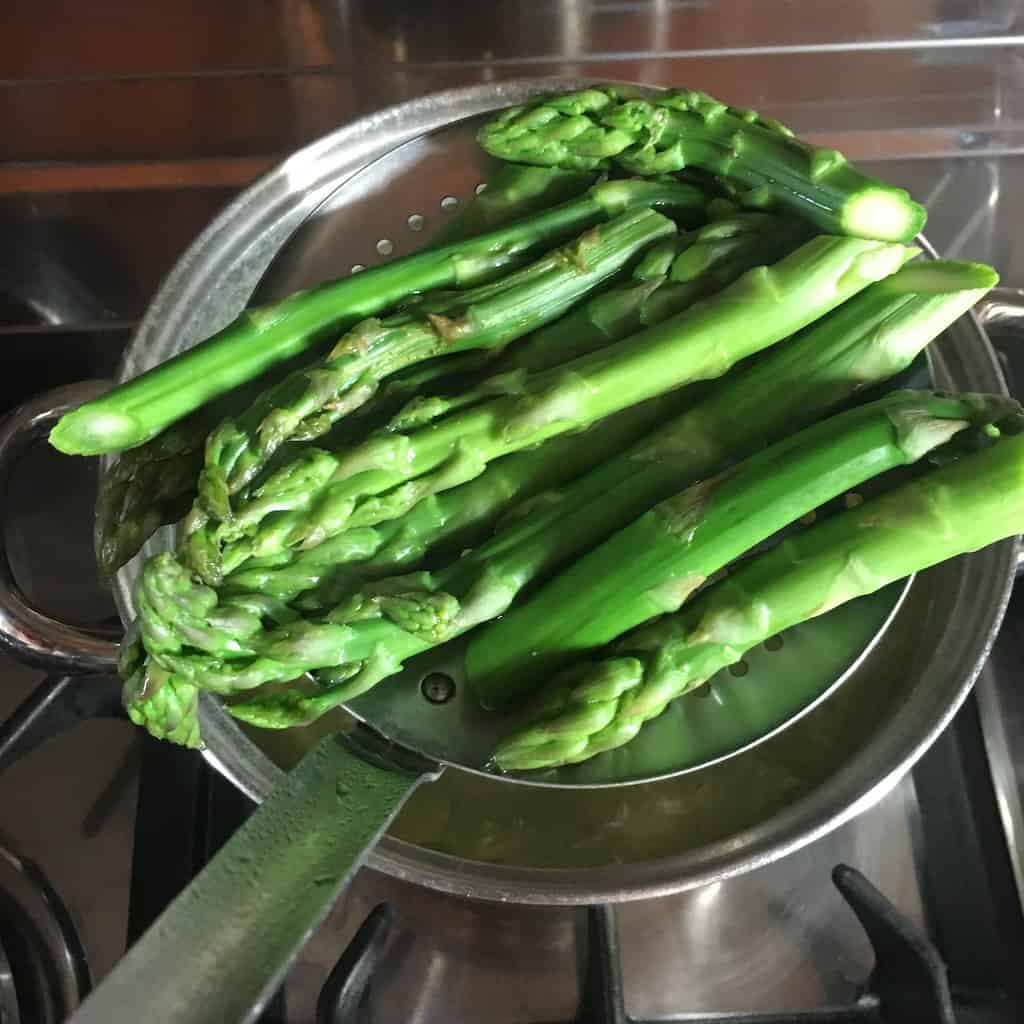 asparagus in a fine mesh sieve being strained