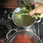 blanching another round of asparagus with my hand holding it just above the pot of boiling water