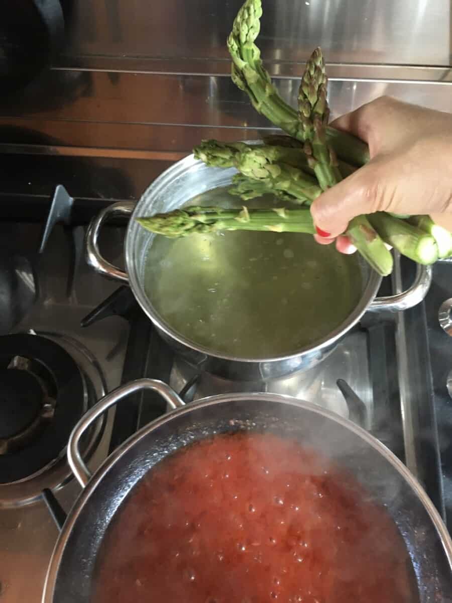 blanching another round of asparagus with my hand holding it just above the pot of boiling water