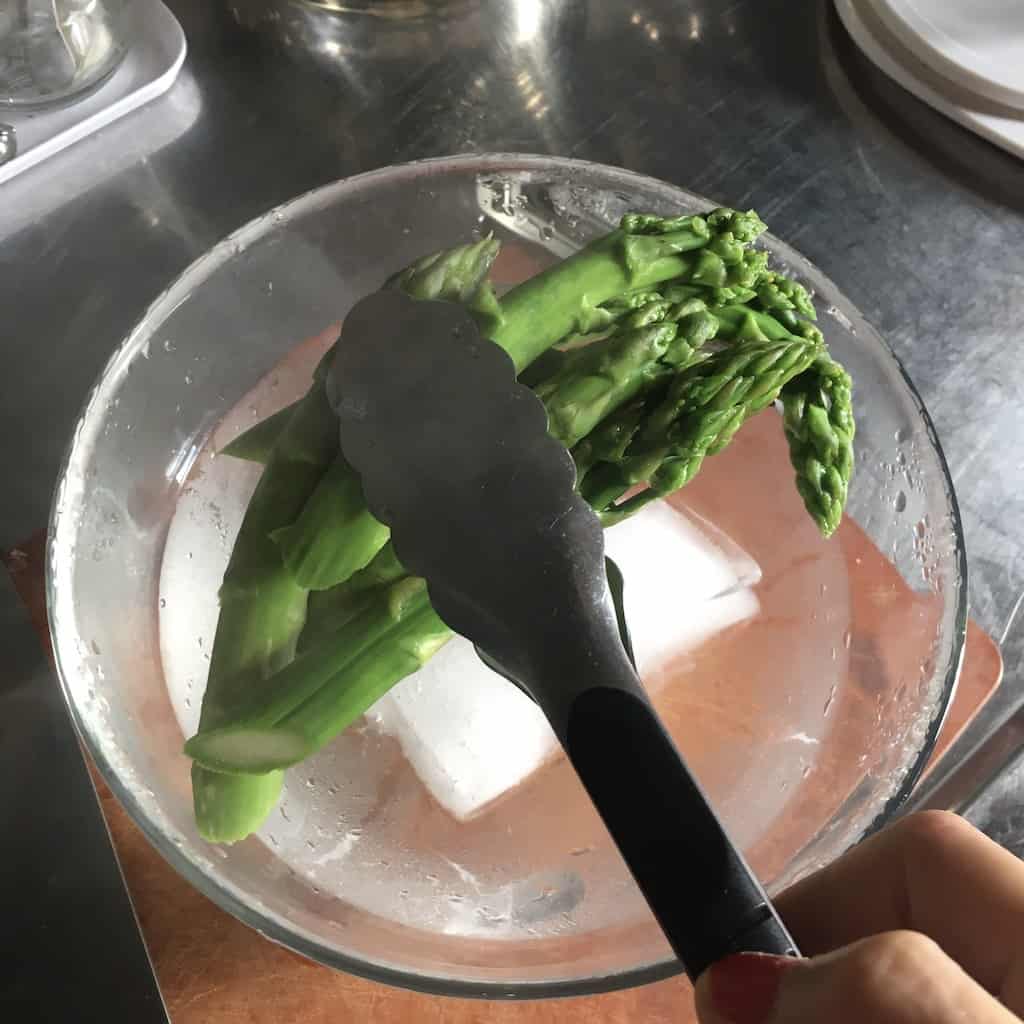 tongs transferring asparagus to the ice bath