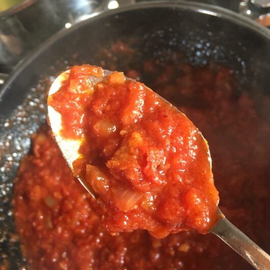 Prosciutto sugo red pasta sauce on a spoon