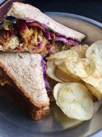 Sesame scallion yellowfin tuna salad on whole wheat bread sliced in half to reveal the best tuna filling and crispy fried onions and shredded purple cabbage for extra texture, served with a side of potato chips. An easy and satisfying lenten lunch idea.