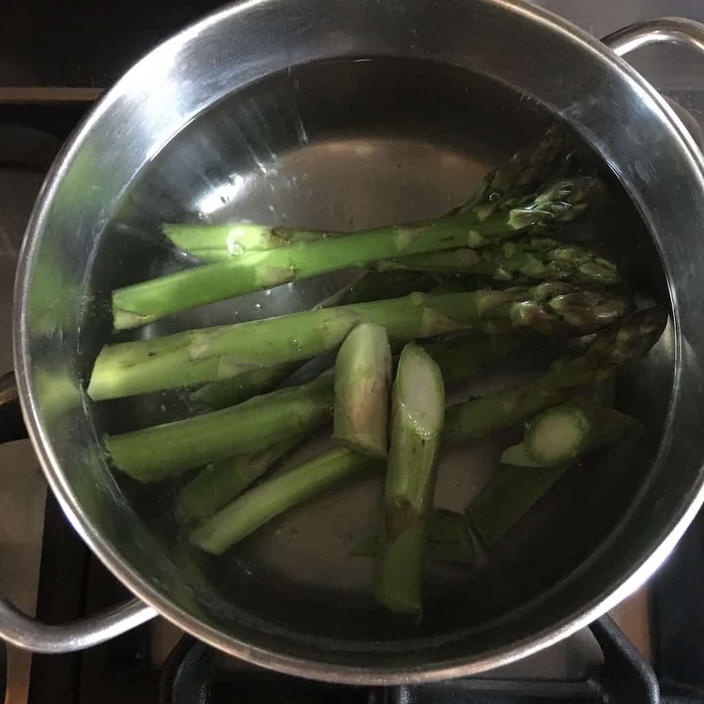 asparagus spears and tips floating in boiling water to be blanced