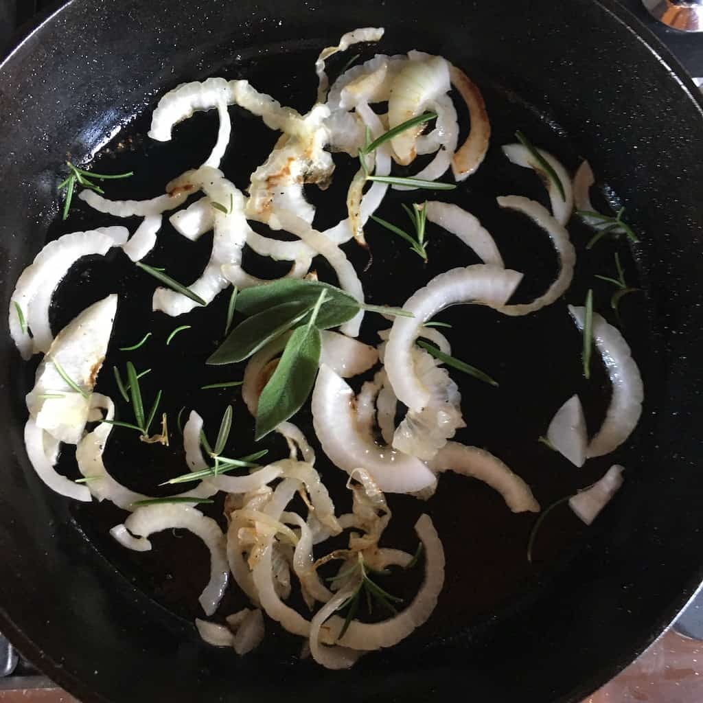onions in a cast iron skillet with herbs