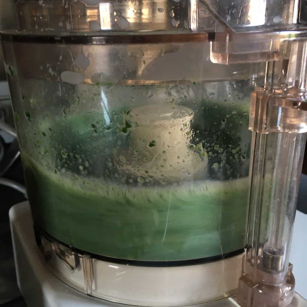 green mixture in bowl of food processor as it's spinning