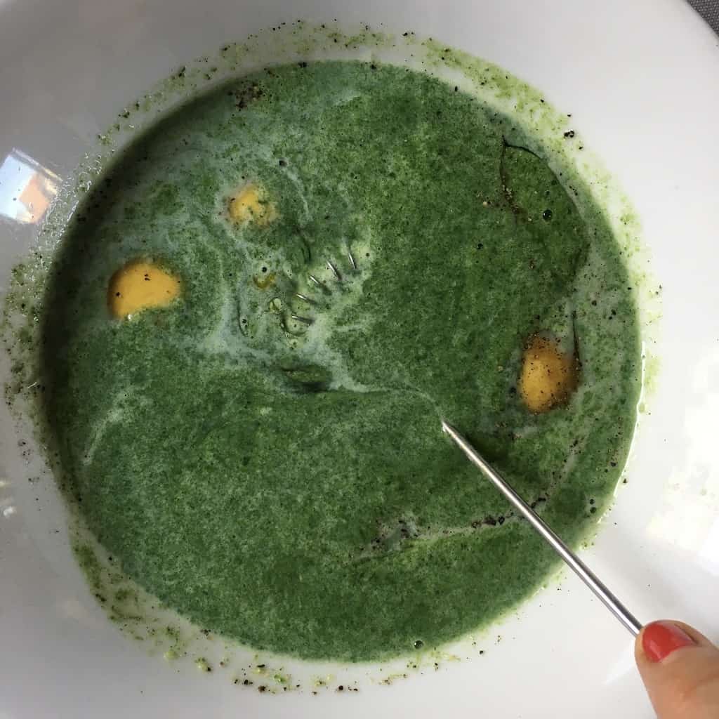 all of the green mixture poured into the 6 eggs cracked into a white bowl with salt and freshly cracked black pepper being whisked