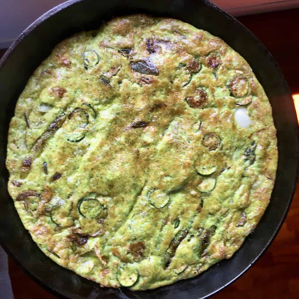 beautifully golden brown frittata in the cast-iron skillet that's been flipped to show off it's perfectly golden underside