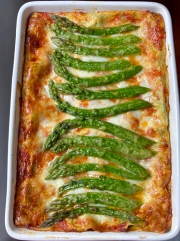 An italian ham and asparagus lasagna fully baked with beautiful wild asparagus spears decorating the top of the cheesy crispy mozzarella topping.