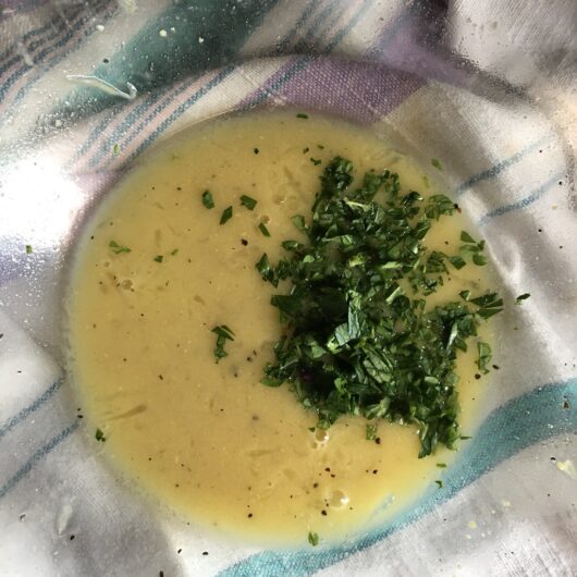 fresh herbs added to the bowl of lemony goodness with a tea towel lying under the bowl