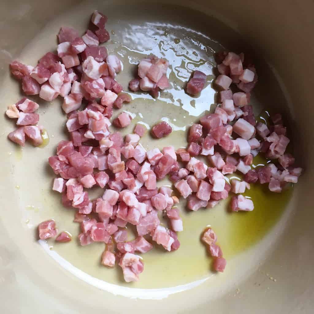 pancetta cubes in a dutch oven cooking with the olive oil