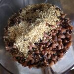 toasted sesame seeds on top of cooked blackeyed peas in the bowl of a food processor