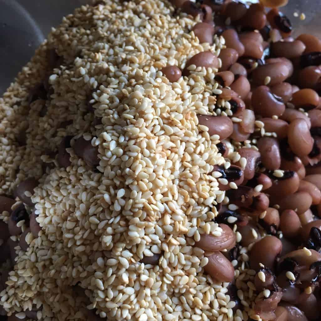 closeup of toasted sesame seeds in a food processor bowl with the cooked blackeyed peas