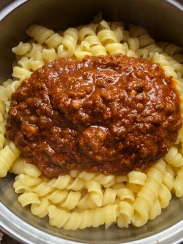 Rustichella cannolicchi pasta topped with bolognese ragu sauce ready to be mixed, pasta bolognese recipe with an authentic Italian ragu bolognese.