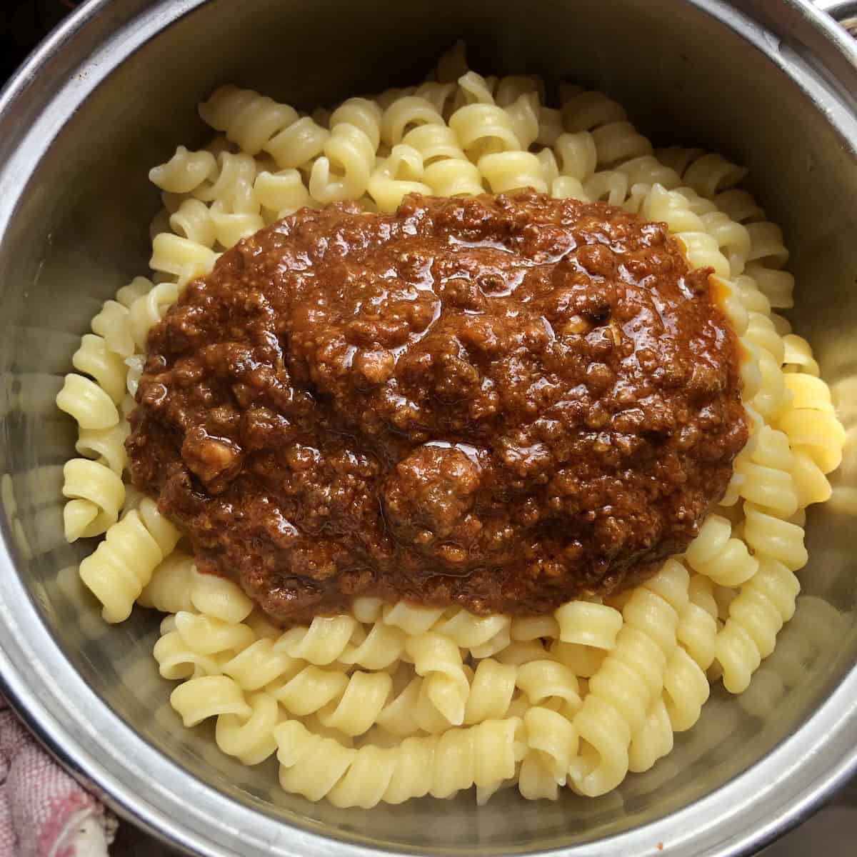 Rustichella cannolicchi pasta topped with bolognese ragu sauce ready to be mixed, pasta bolognese recipe with an authentic Italian ragu bolognese.
