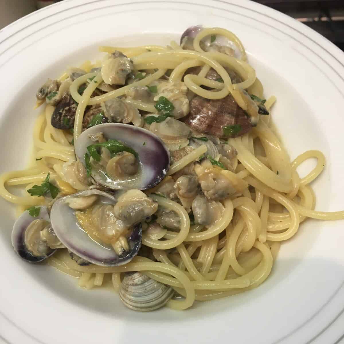 white pasta bowl filled with a large serving of spaghetti with clams