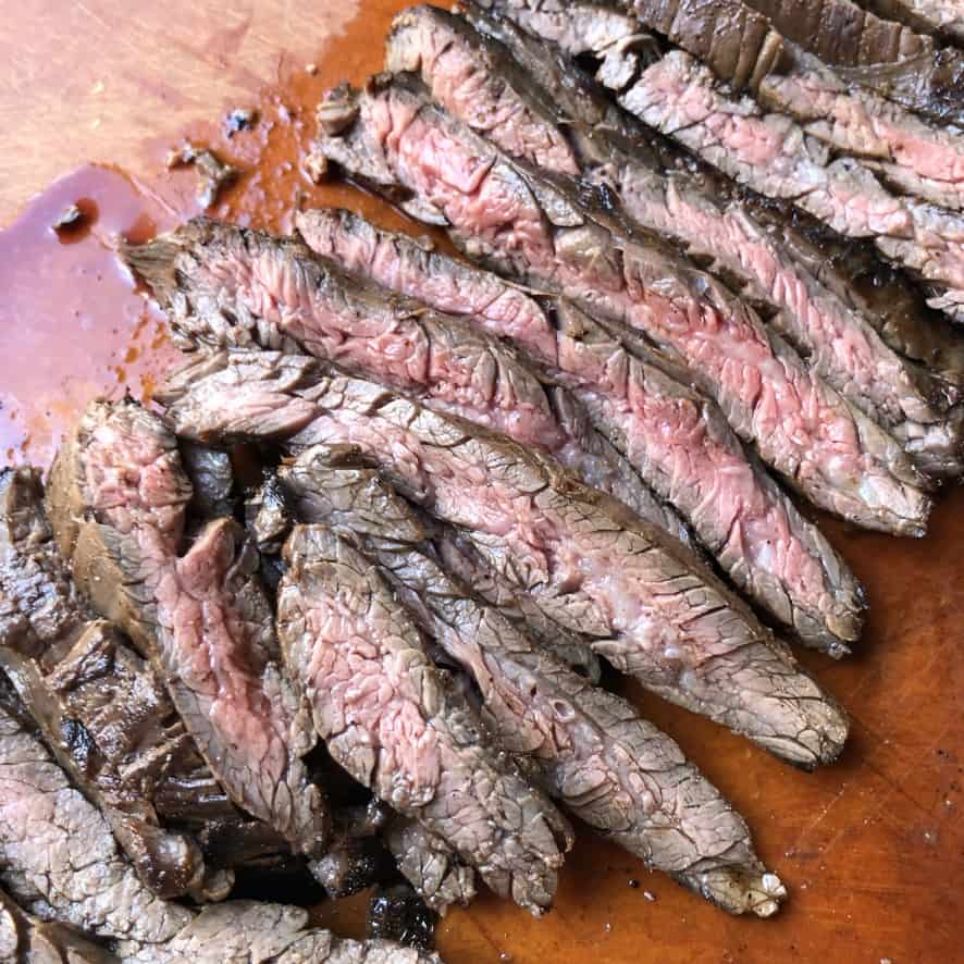 flank steak cooked medium and sliced on a cutting board