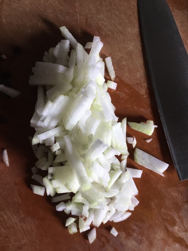 onions chopped to a fine dice on a cutting board with Global 8" knife next to it
