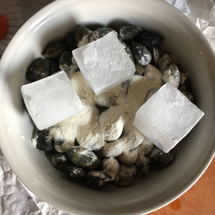 Step 5: Removing opened clams with tongs to a bowl to prevent overcooking, leaving remaining clams to finish.