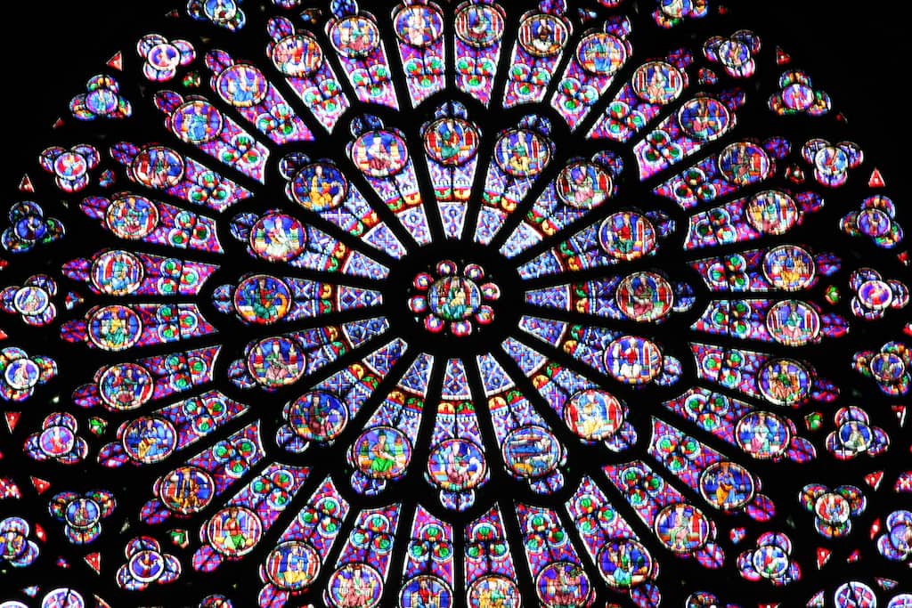 Beautiful stained glass windows of Notre Dame Cathedral in Paris, France with blues, reds, yellows and greens being the dominant colors