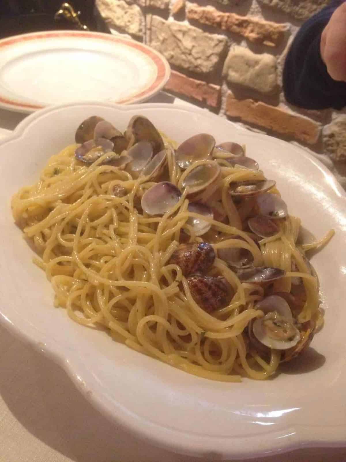 Spaghetti with clams on oval platter from a restaurant in Sicily, Italian clam recipe with fresh vongole.