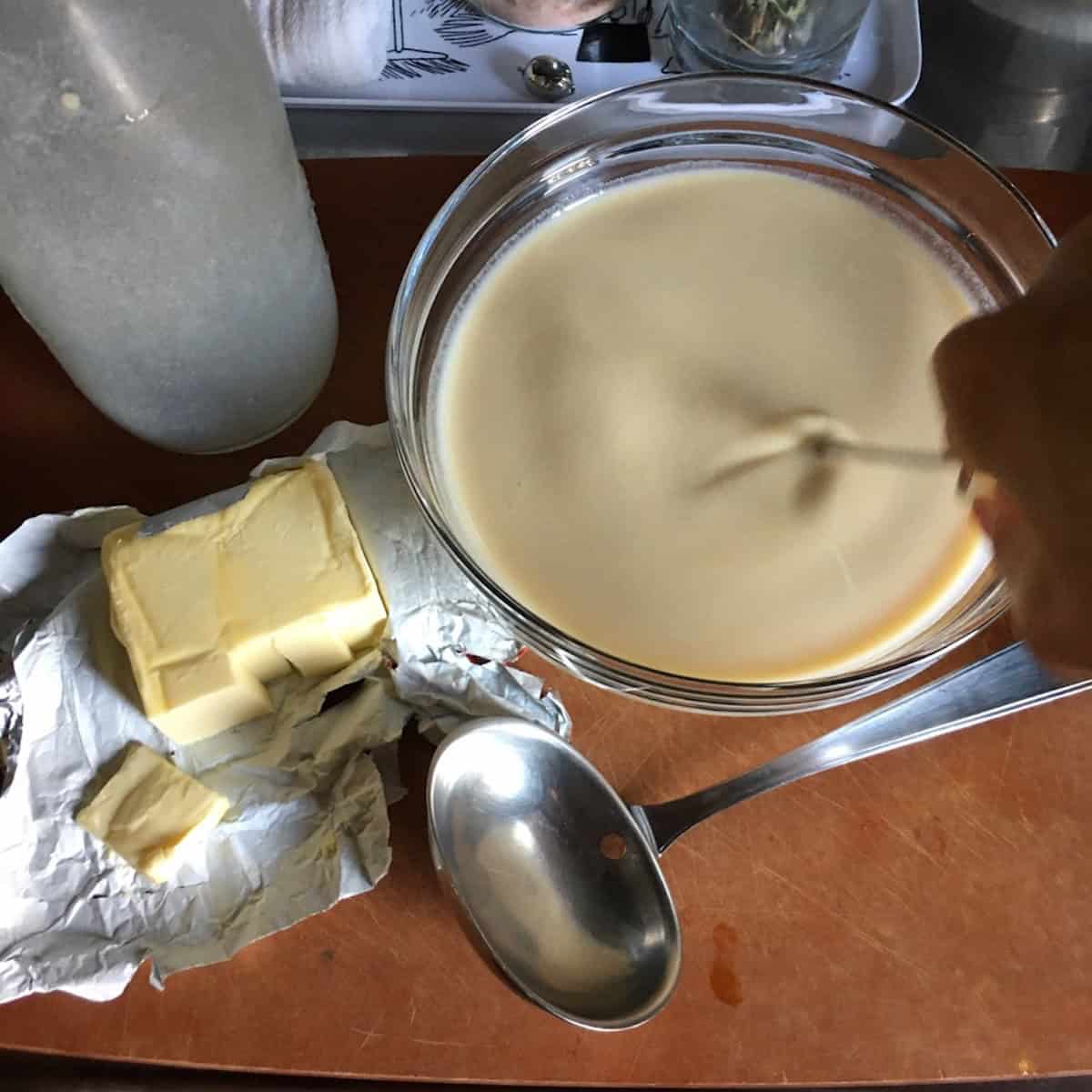 Whisking rested crepe batter to restore smooth crepe batter consistency, a key step in how to make crepe batter for perfect crepes.
