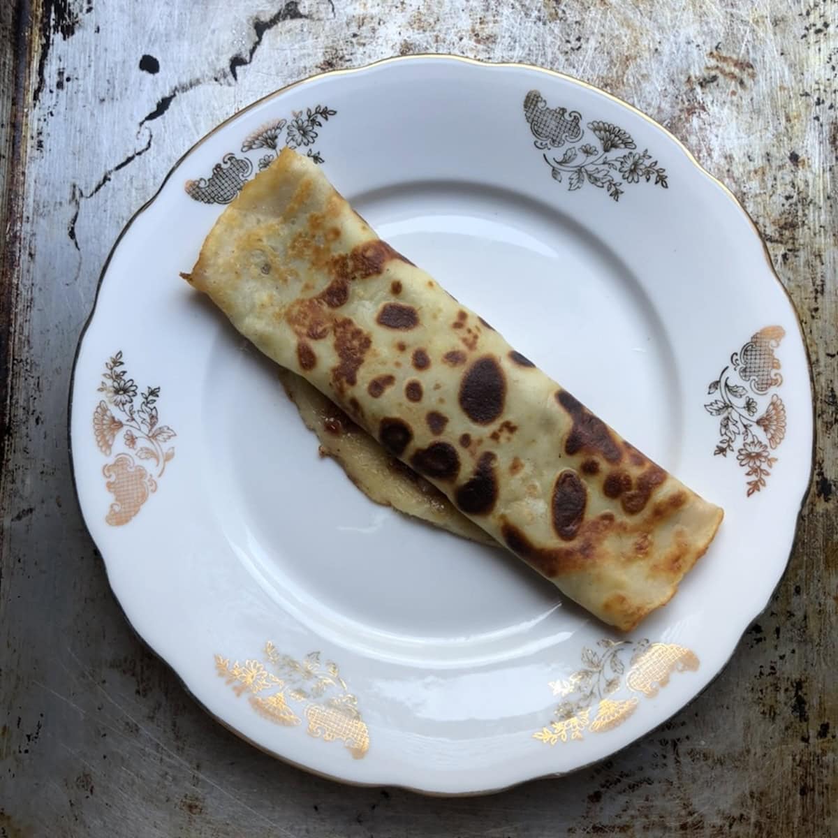 A crepe rolled up burrito style showing how to fold crepes, one of the easiest crepe rolls methods for any crepe filling recipe.
