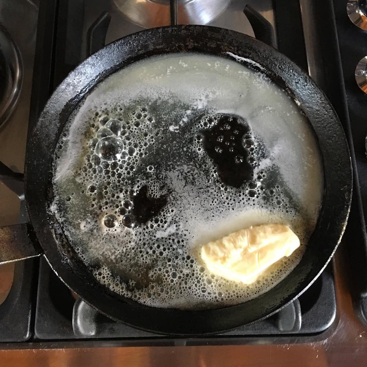 Butter melting in a crepe pan as a step in how to make crepe batter for this french crepes recipe, adding rich flavor to a simple crepe recipe.