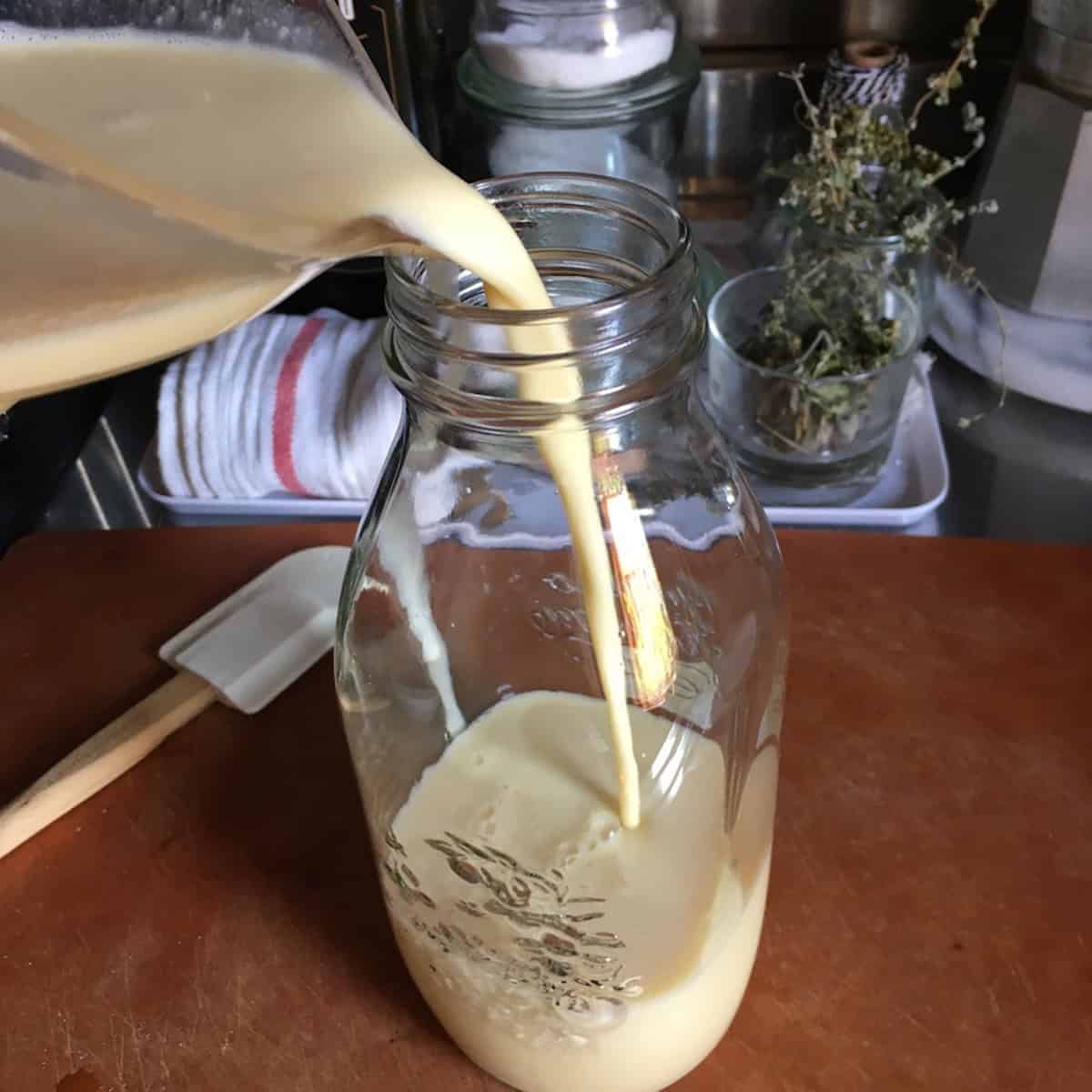 Pouring crepe batter into a glass canning jar for overnight rest in the fridge, a simple crepe batter storage tip from this crepes recipe for the best crepe batter consistency.
