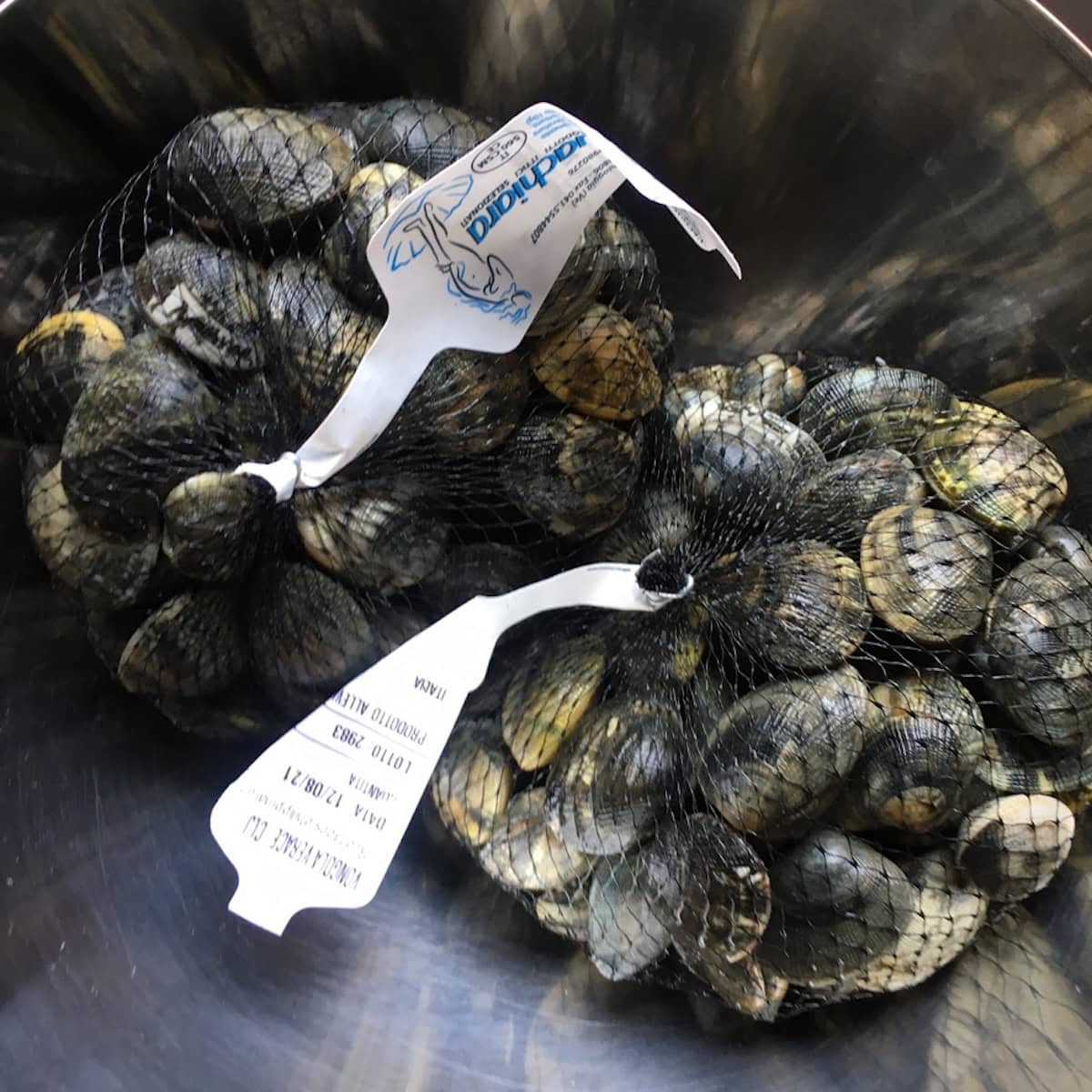 Two mesh bags with 1 kg each of fresh vongole veraci clams, how to store clams before using for clam sauce recipe.