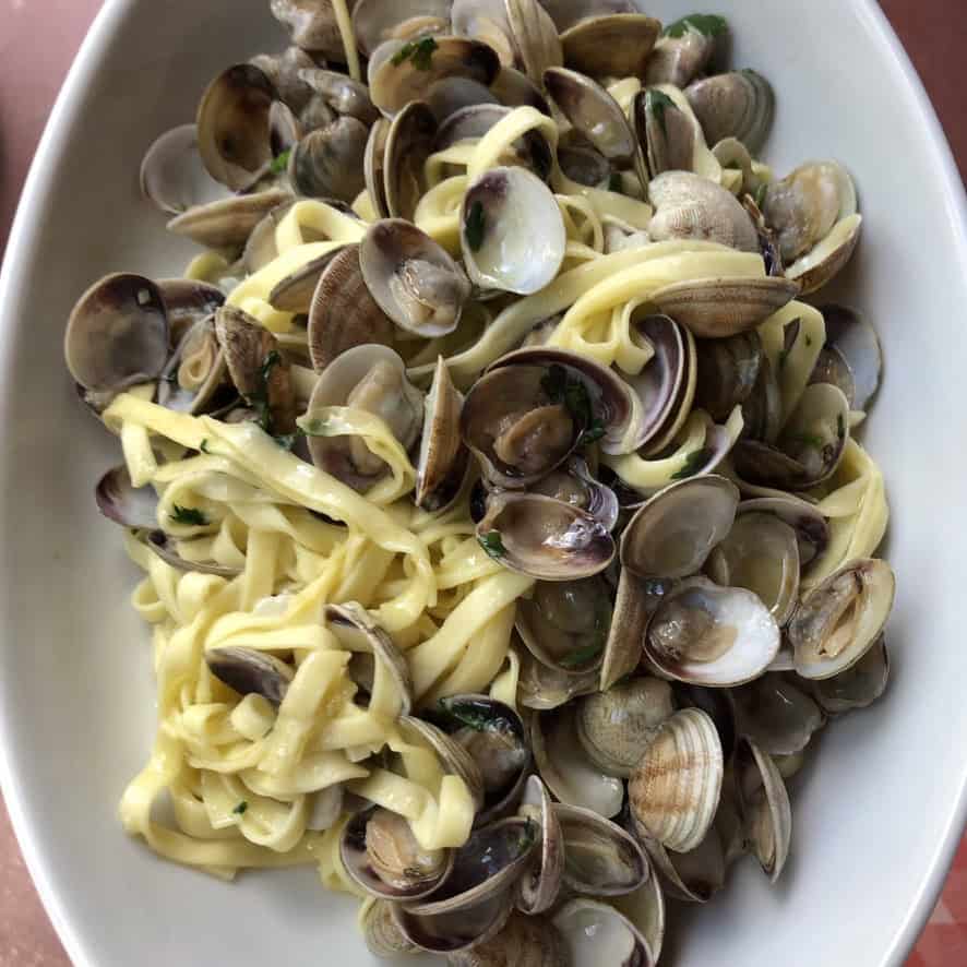 Linguine alle vongole on oval platter from a seaside trattoria in southern Italy, handmade linguine vongole filled with veraci clams.
