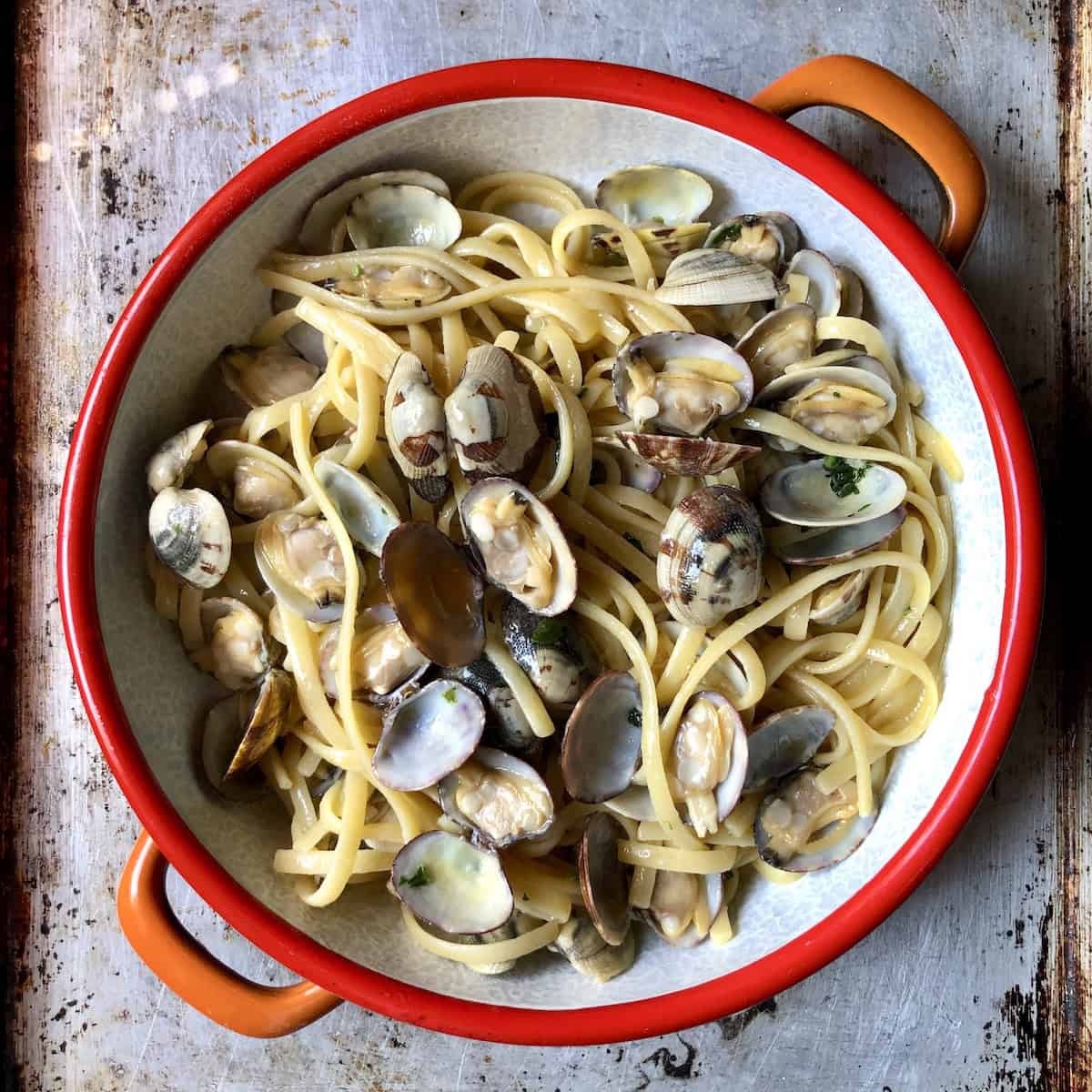 Full view of homemade linguine with clam sauce with whole veraci clams in a shallow serving dish, clam sauce recipe in white wine from scratch.
