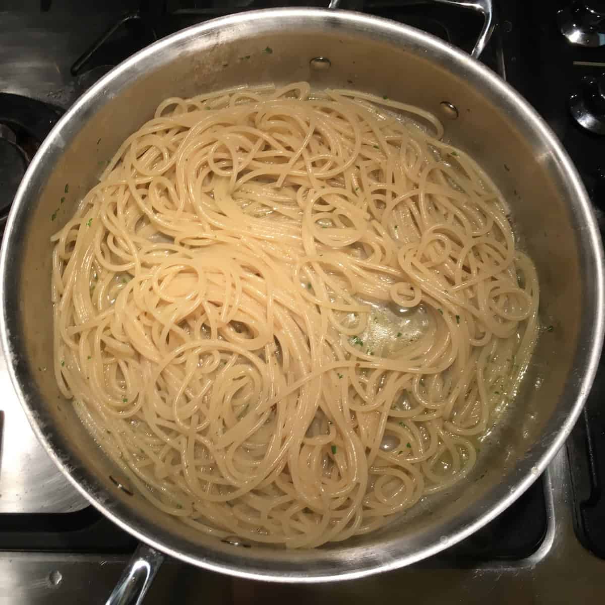Perfectly cooked al dente spaghetti in silky emulsified clam sauce ready for clams to be added, spaghetti alle vongole almost finished.
