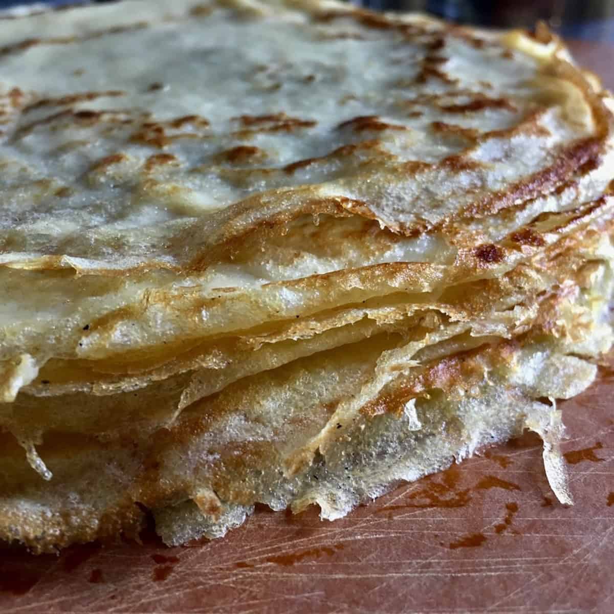 A stack of golden brown perfect crepes from this french crepe recipe, showing thin and tender results from the best basic crepe recipe for sweet crepe recipe or savory crepe recipe.
