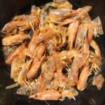 cooked shrimp heads and tails in a black pan