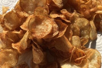 super thin and crispy homemade potato chips on a white paper towel in the sunlight