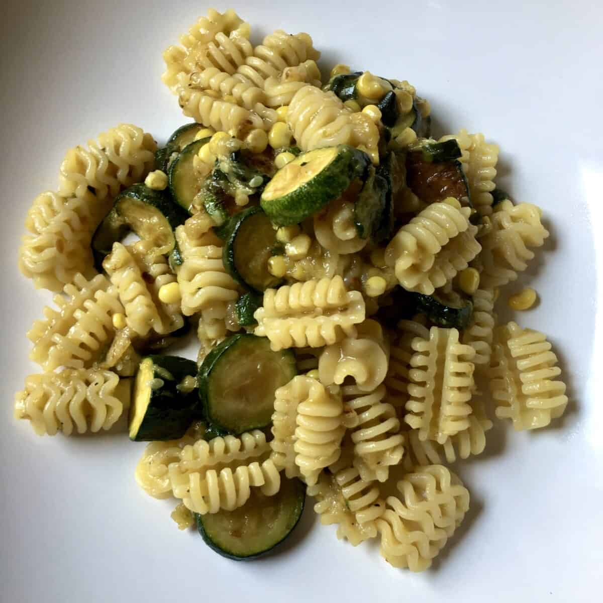 Pasta bowl filled with creamy corn and zucchini pasta with radiatore pasta shape for the perfect summer pasta recipe.