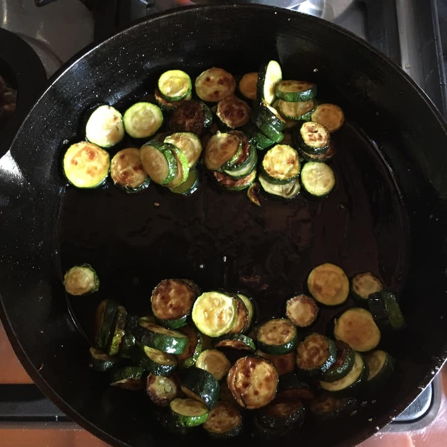 a skillet divided with zucchini rounds on each half