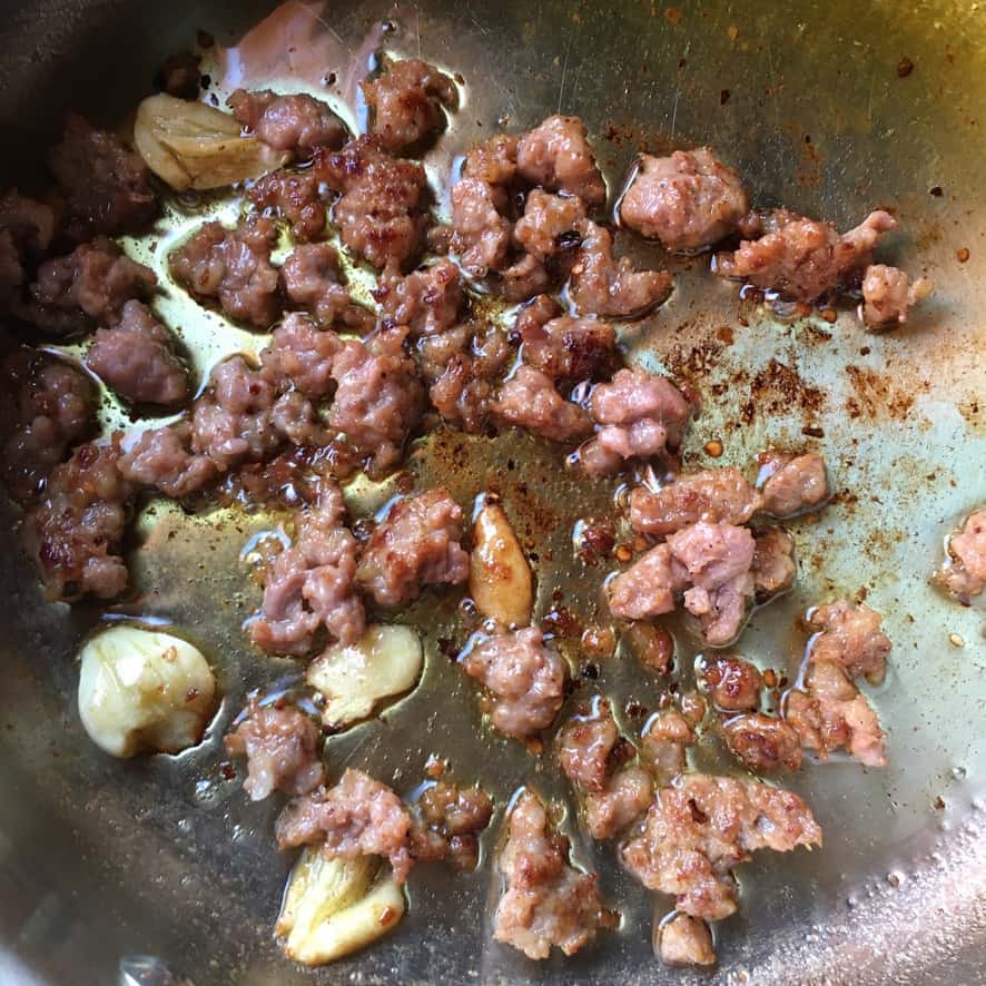 garlic and sausage in the pan with olive oil browning