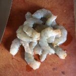 raw shrimp with heads and shells removed lying on a cutting board