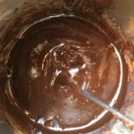 shiny chocolate ganache icing in a bowl with a whisk