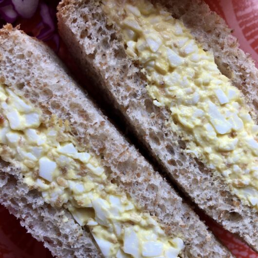 closeup of sesame egg salad on whole wheat bread that's been cut into triangles and the middles facing out and up towards you
