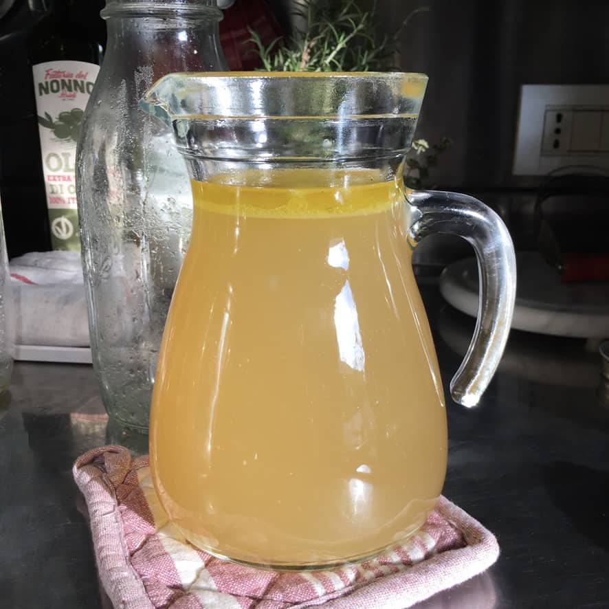 a clear glass pitcher full of homemade chicken stock