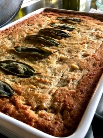 Closeup of the best Southern cornbread dressing with crispy sage leaves garnishing the top for decoration (crispy buttery edges and super moist filling).